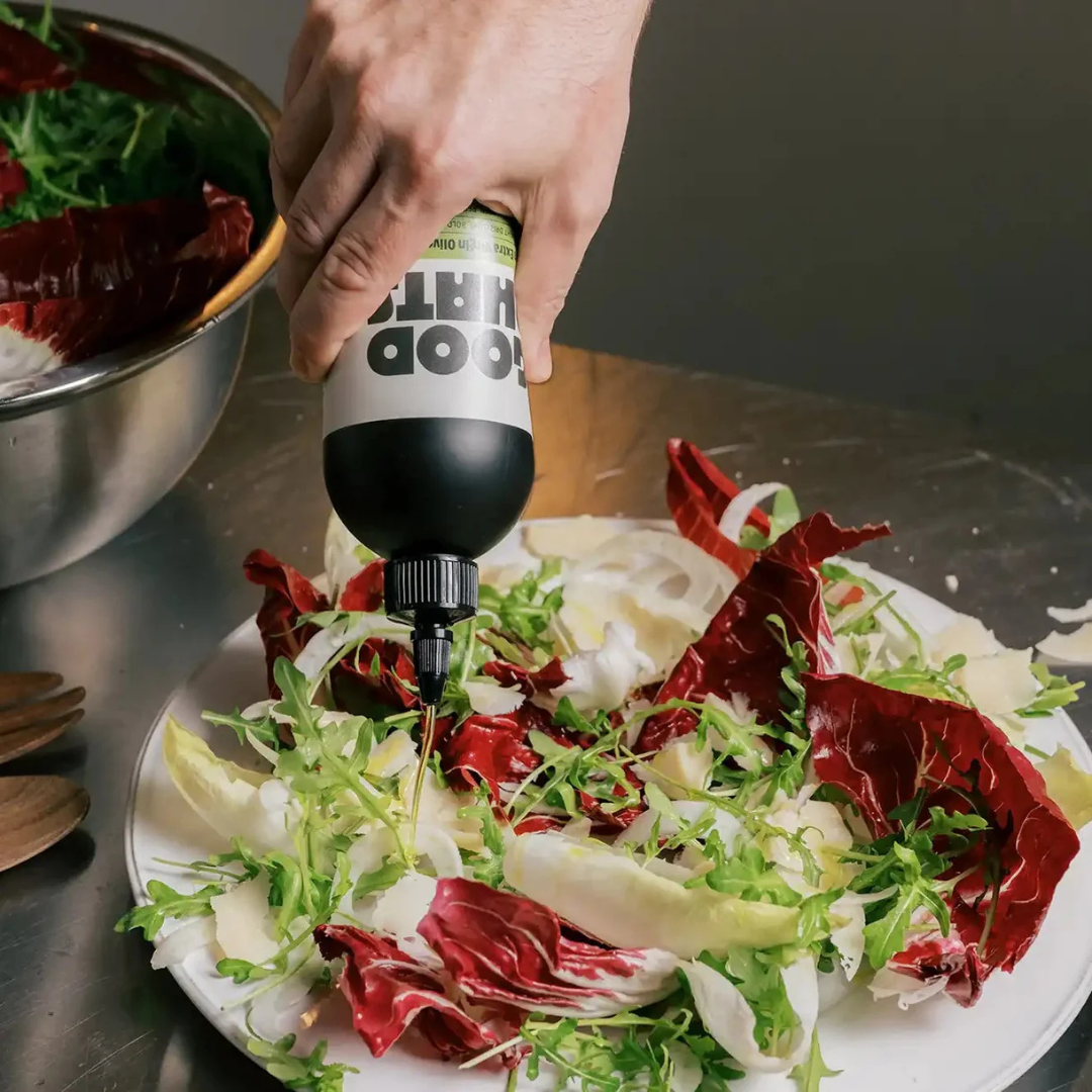 GOOD PHATS Italian extra virgin olive oil in a squeeze bottle drizzled over a fresh leaf salad